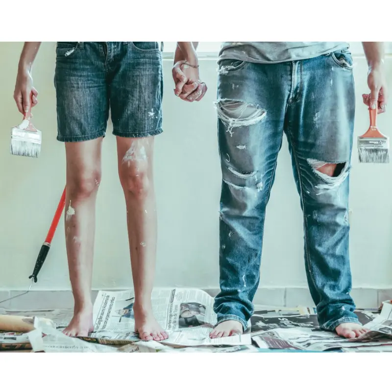 Frustirani mladi bračni par tokom renoviranja kuce, okruženi alatima i rasparenim planovima